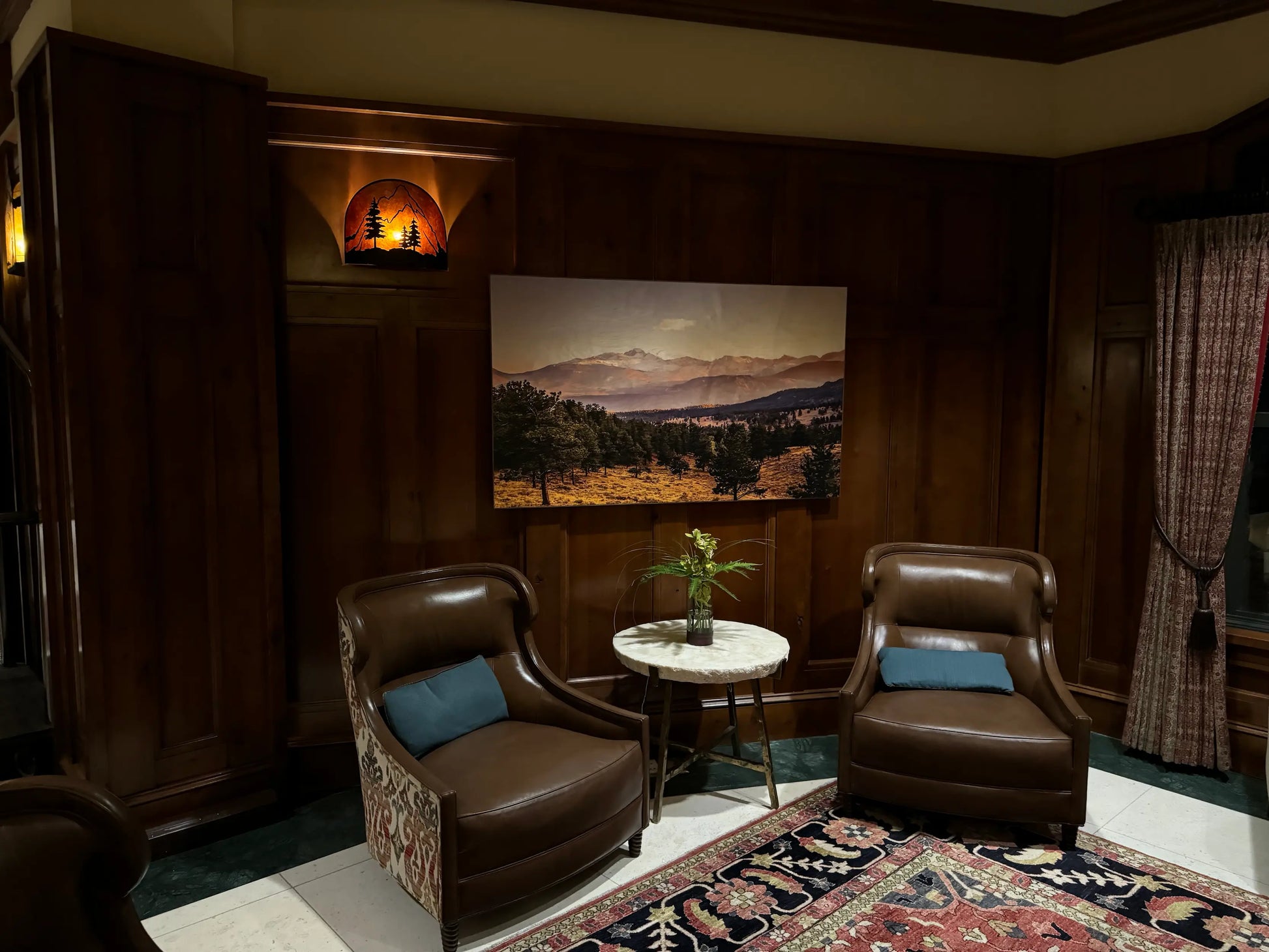 Cozy living room with brown leather chairs, a small table, and a scenic wall art.