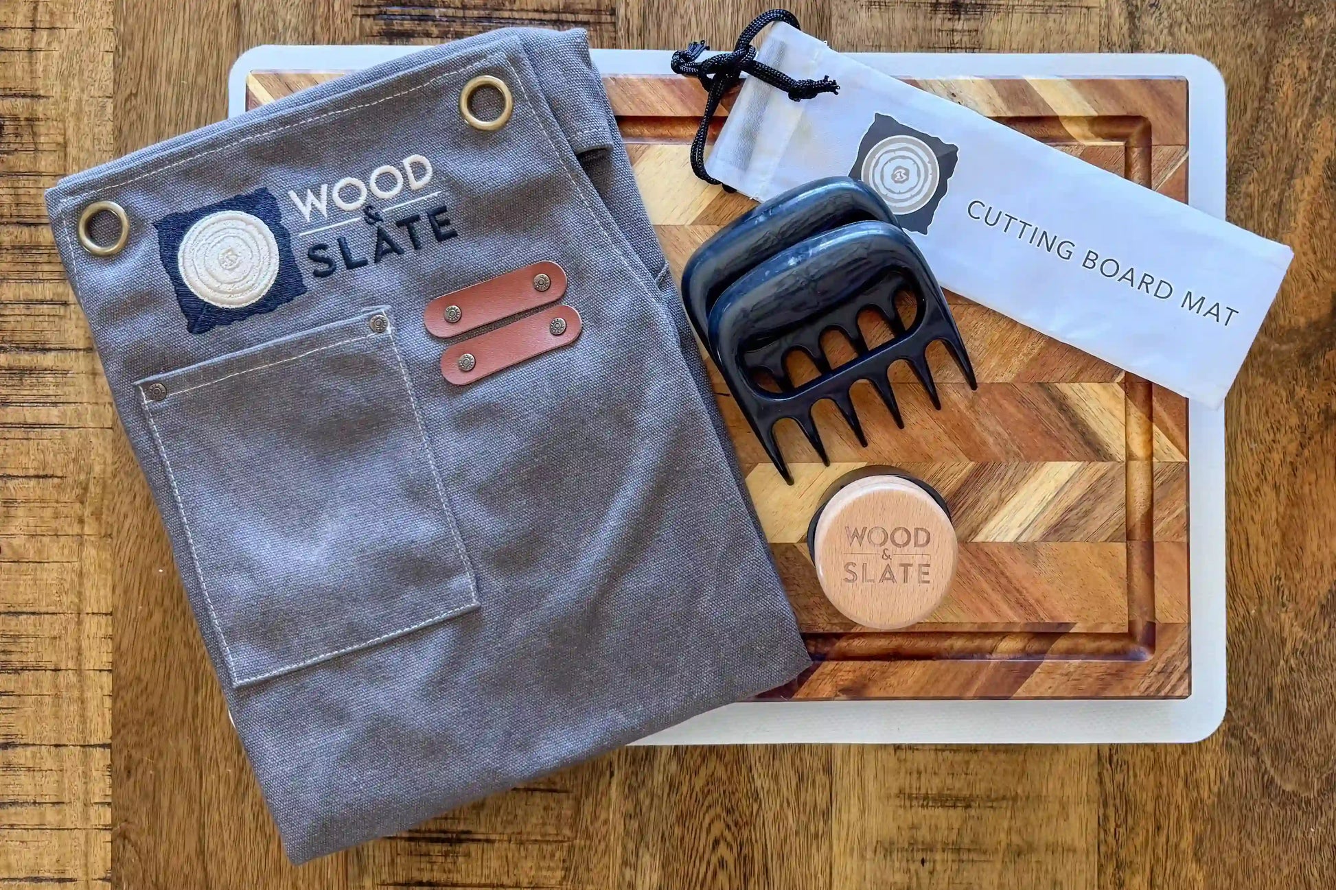 Gray apron with leather accents on a wooden surface, featuring 'Wood Slate' branding.