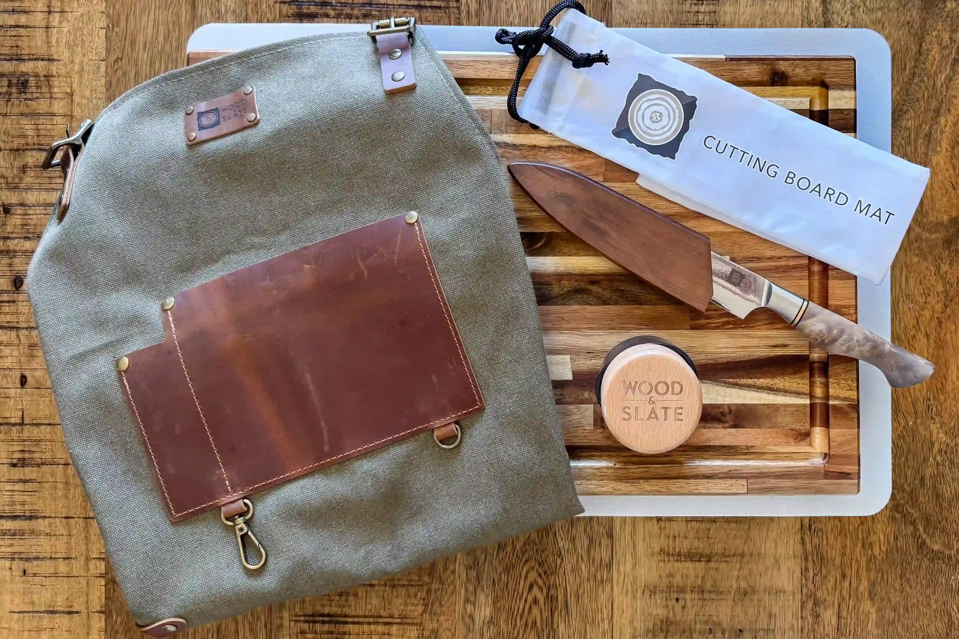 Green leather bag with brown leather patch on a wooden surface with cutting board and knives.