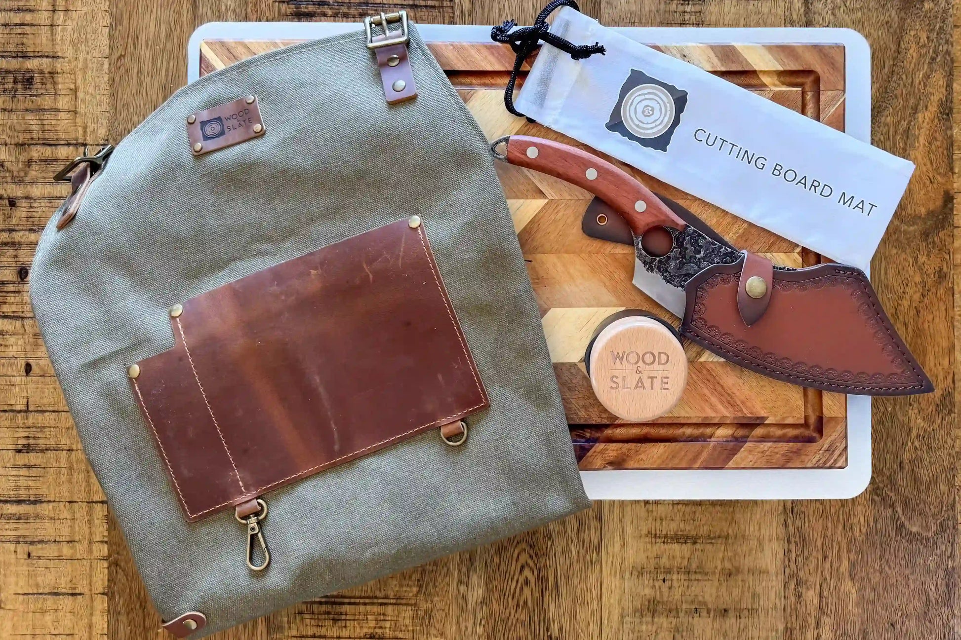 Gray backpack with leather accents on a wooden surface with a cutting board and knife set.